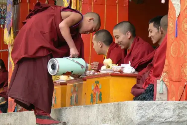 Monges budistas tibetanos reunidos em um mosteiro, compartilhando chá de manteiga tradicional como parte de um ritual comunitário.